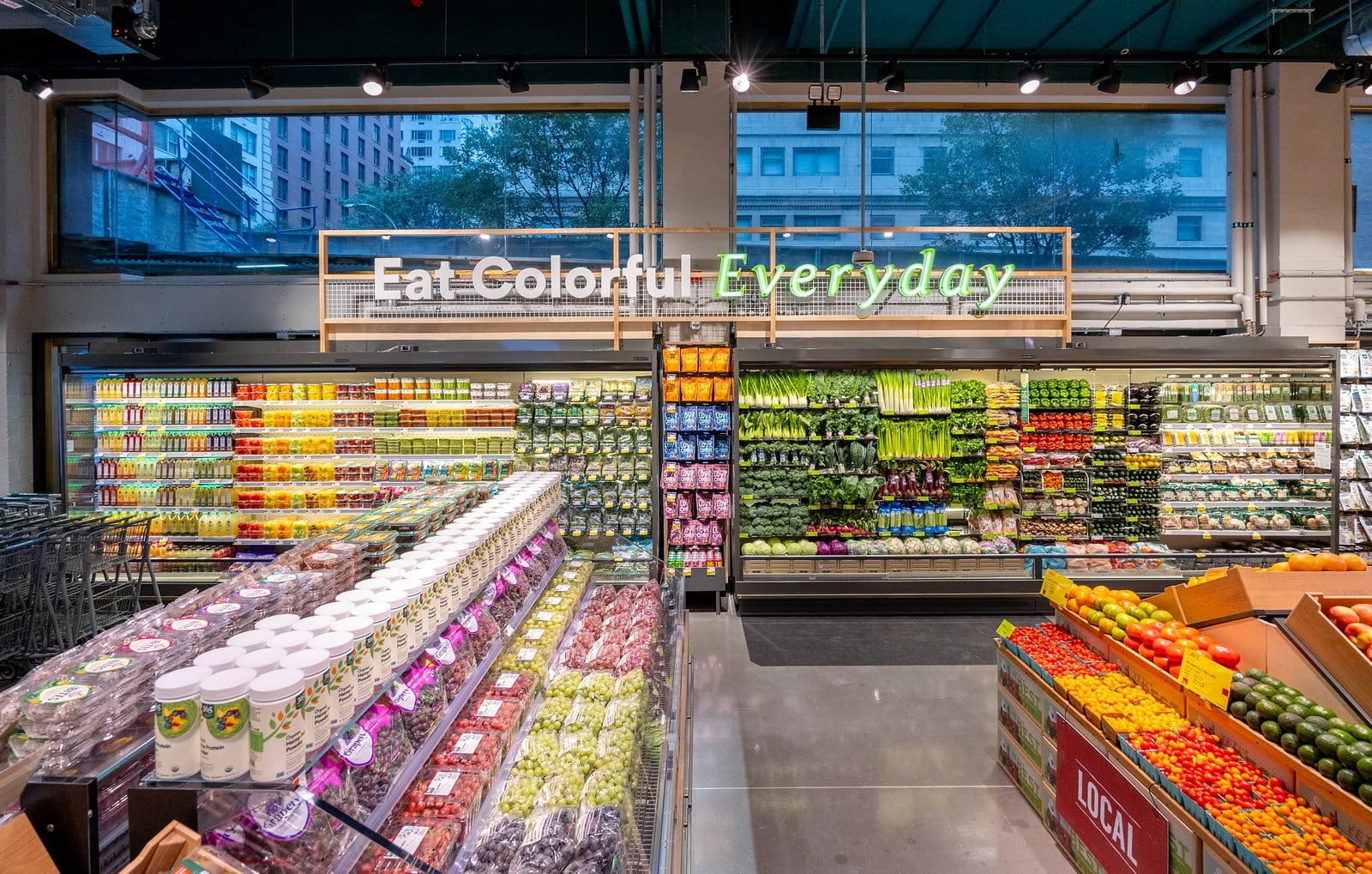Retail produce display with Eat Colorful Everyday signage — grocery shelf placement by Mana Foods